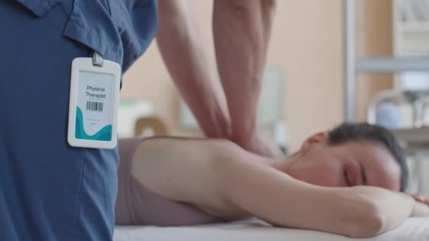 Colpo ritagliato di terapeuta manuale che restituisce massaggio alla paziente sdraiata sul divano medico durante la terapia in clinica - Filmati, video