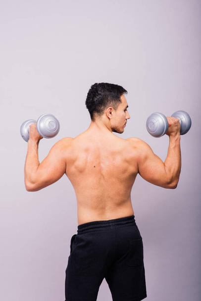 Shirtless bodybuilder showing his great body and holding dumbells. - Valokuva, kuva