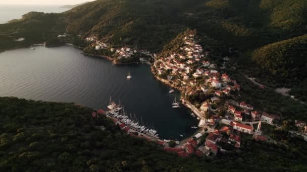 Légi kilátás tengerparti falu Görögországban. Gyönyörű kilátás, sziget zöld dombokkal, házak és kikötő csónakokkal. Földközi-tengeri üdülőhely - Felvétel, videó