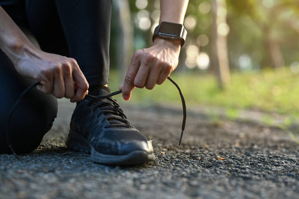 Gros plan femme sportive agenouillée et attachante lacet prêt pour le jogging matinal. - Photo, image