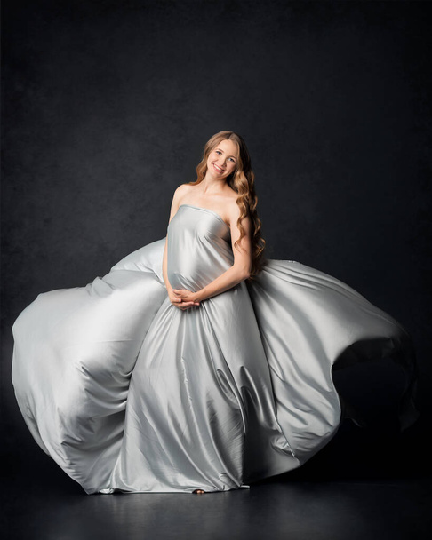 Pregnant woman on black background with big tummy, waiting for baby. Pregnancy, motherhood concept - Фото, зображення