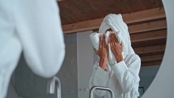 tratamiento de belleza para la piel de la cara mujer adulta con toalla en el pelo vestido blanco albornoz de pie delante del espejo - Metraje, vídeo
