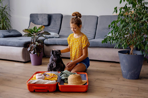 Jeune voyageuse heureuse se préparant pour un voyage de vacances d'été vacances avec sa valise jaune vif prêt à être emballé - Photo, image