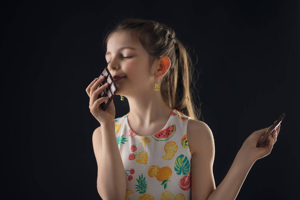 Schokolade und ziemlich hungrige kleine Frau Porträt. Schöne Mädchen bereit, Schokoriegel zu essen. - Foto, Bild
