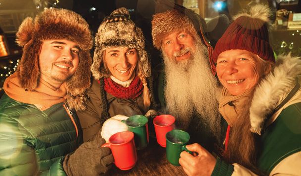Szczęśliwa rodzina toasting z kubki grzanego wina i gorącej czekolady na rynku Bożego Narodzenia, noszenie czapki zimowe - Zdjęcie, obraz