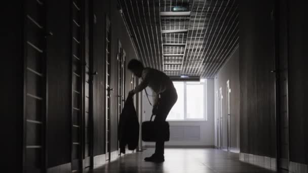 Повний знімок невпізнаваного чоловіка, що біжить по темному коридору, запізнюється, щоб зустрітися, намагаючись швидше одягнути блискавку - Кадри, відео