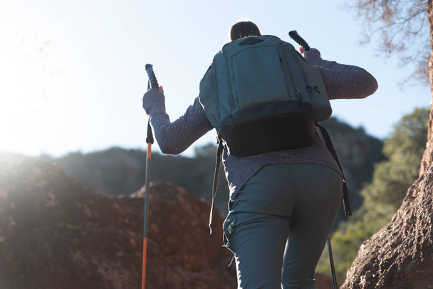 Woman climbs the mountain in the Garraf Natural Park, supported by hiking sticks. - Photo, Image
