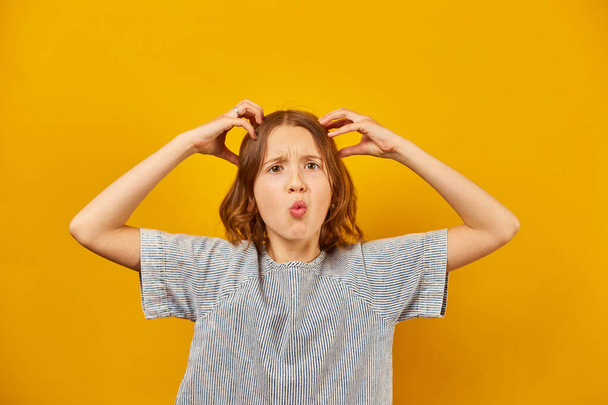 Teen girl portrait, facial gesture, teenage emotions, disapproval concept, dislike crazy idea in yellow studio background - Photo, Image