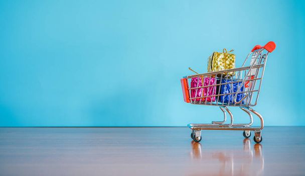 carrito de compras con un carrito de supermercado sobre un fondo azul - Foto, imagen