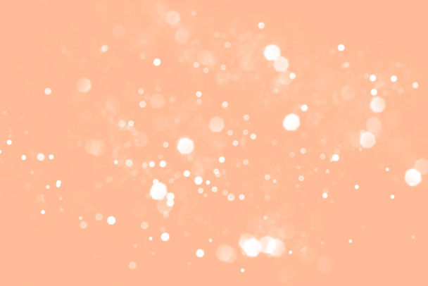 White blurred abstract bokeh lights on peach fuzz background. Snowy shiny glitter sparkle stars for celebrate - Photo, Image