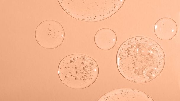 Top view of liquid cosmetics gel with bubbly structure on pastel background.Peach fuzz colored. - Photo, Image