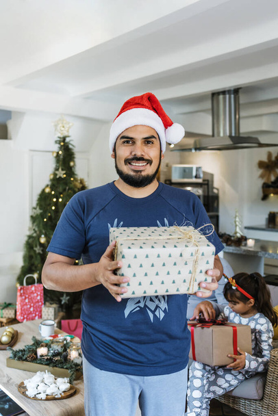 Latinalainen mies avaamalla lahjoja joulun tai lomien aikana kotona Meksikossa Latinalaisessa Amerikassa, latinalaisamerikkalainen ihmiset lomilla - Valokuva, kuva