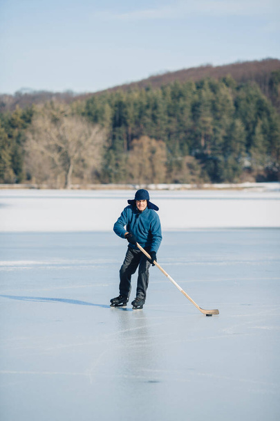 Un uomo anziano pratica hockey su ghiaccio su un lago ghiacciato in inverno. - Foto, immagini