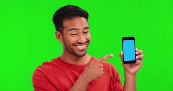 Man, face and point at cellphone by green screen with smile, review and choice with mock up space for app logo. Student guy, phone and happy for decision for branding, agreement and studio portrait. - Footage, Video