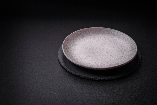 Prázdný kulatý keramický talíř jako kus kuchyňského nádobí na texturovaném betonovém pozadí - Fotografie, Obrázek