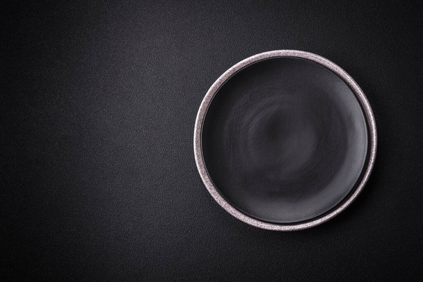 Plaque céramique ronde vide comme ustensiles de cuisine sur fond de béton texturé - Photo, image