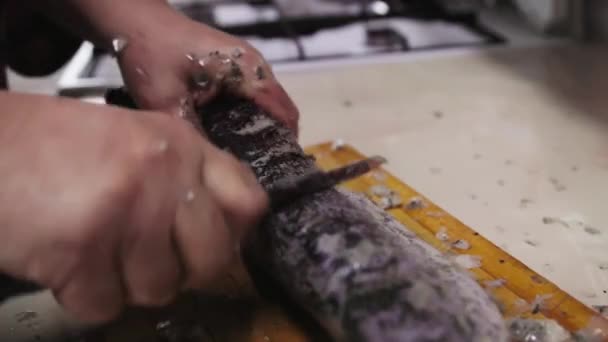 vrouw verwijderen van schaal van luce vis met klein mes op houten plank in de keuken. - Video