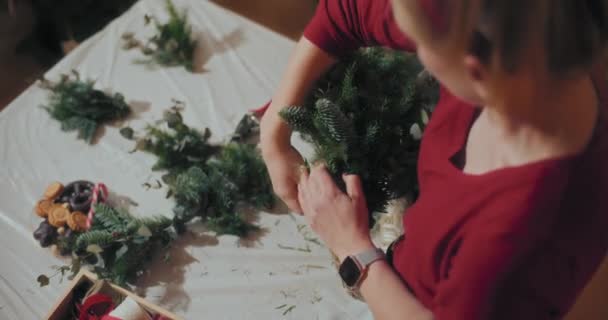 Вид Флориста Подготовка традиционного Рождественского венка к рождественским праздникам - Кадры, видео