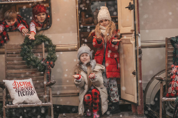 Enfants célébrant Noël et Nouvel An saison des fêtes d'hiver en plein air attendant le Père Noël. Enfants joyeux passer du temps ensemble près de caravane camping-car de Noël se réjouit à la première neige profiter de l'enfance - Photo, image