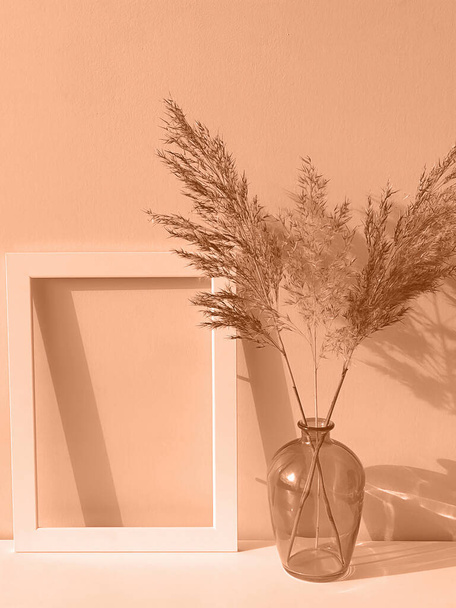 ピーチファズは2024年の色です. フレーム,ガラス花瓶,乾いた花は,ピンクオレンジのトレンドセッティングカラーをブレンドしました ピーチファズ - 写真・画像