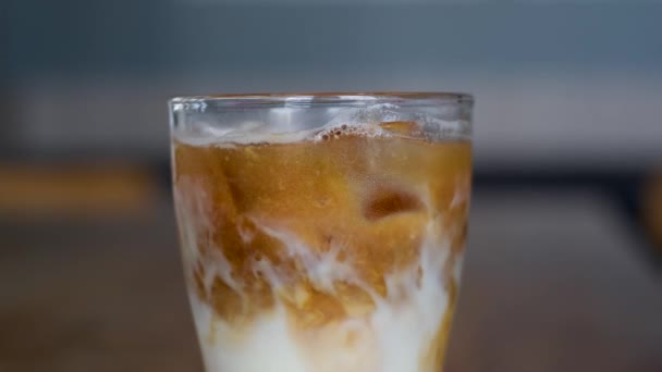 Makroaufnahme von kaltem Kaffee. In Zeitlupe aufgenommen, wie eine Frau Eiswürfel in zubereiteten Kaffee wirft. Eiswürfel schwimmen auf der Oberfläche des Kaffees. Sondenlinse. Hochwertiges 4k Filmmaterial - Filmmaterial, Video