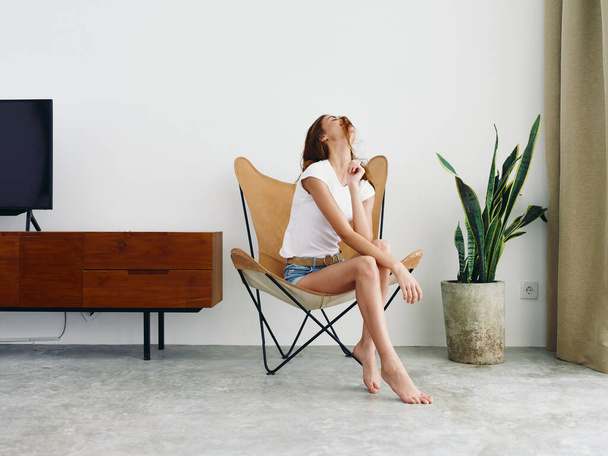 Женщина сидит в кожаном кресле улыбка с зубами стиль жизни, расслабляющий дома стильный современный интерьер с белыми стенами, копировальное пространство. Высокое качество фото - Фото, изображение
