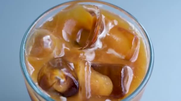 Macro view of cold coffee. Slow motion shot how woman throws ice cubes into prepared coffee. Ice cubes float on the surface of the coffee. Probe lens. High quality 4k footage - Footage, Video