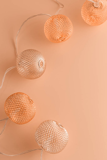 Close-up Christmas garland with metallic balls on table colored in Peach Fuzz - color of the year 2024. - Photo, Image