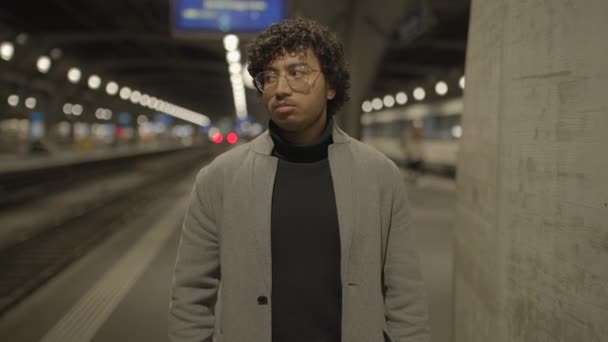 Un hombre con el pelo rizado negro esperando solo en la estación de tren por la noche. Imágenes de alta calidad 4k - Imágenes, Vídeo