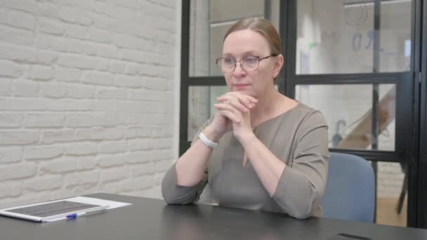 Σκεπτική ηλικιωμένη γυναίκα κάθεται στο γραφείο - Πλάνα, βίντεο