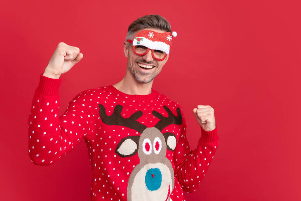 Boldog ember téli pulóverben és parti mikulás szemüvegben. Karácsonyi fickó piros háttérrel. Boldog új évet! Boldog karácsonyt!. - Fotó, kép