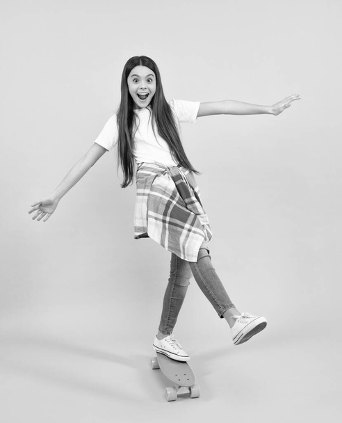 Mode tiener levensstijl, mooie tiener meisje met skateboard geïsoleerd op studio achtergrond. gelukkig tiener, positieve en lachende emoties van tiener meisje - Foto, afbeelding