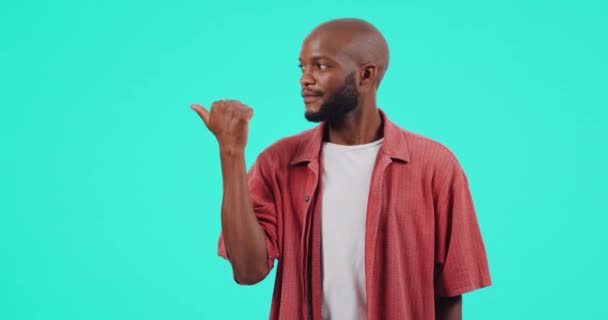 Face, pointing and black man with promotion, surprise and winning against a blue studio background. Portrait, male person and model with hand, mockup space and announcement with giveaway and shocked. - Footage, Video