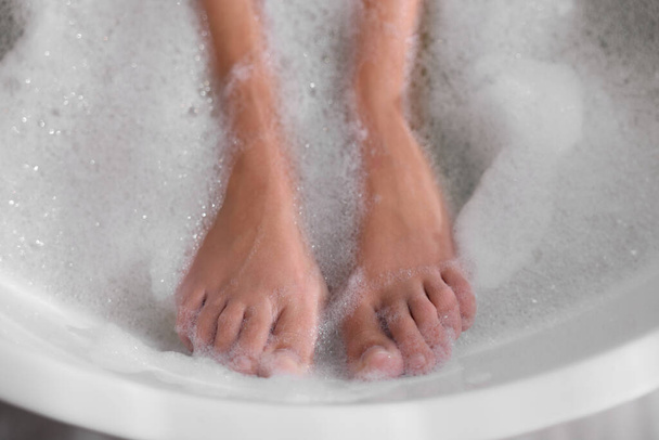 Woman taking bath in tub with foam, closeup - 写真・画像