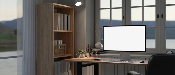 Moderner Home-Office-Arbeitsplatz mit einer PC-Computerattrappe mit weißem Bildschirm und Zubehör auf einem Schreibtisch und einem Bücherregal neben dem Fenster. 3D-Renderer, 3D-Illustration - Foto, Bild