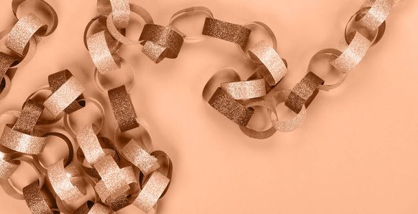 Strips of gold silver red sparkling chain garland. Image toned in Peach Fuzz color of the year 2024. Festive Christmas birthday decoration garland. Space for text - Photo, Image