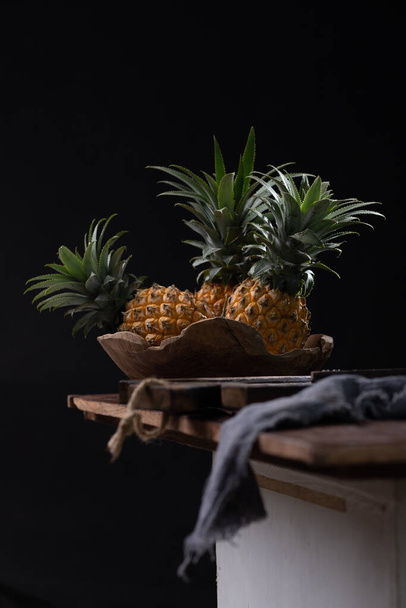 nature morte avec ananas sur une table en bois - Photo, image