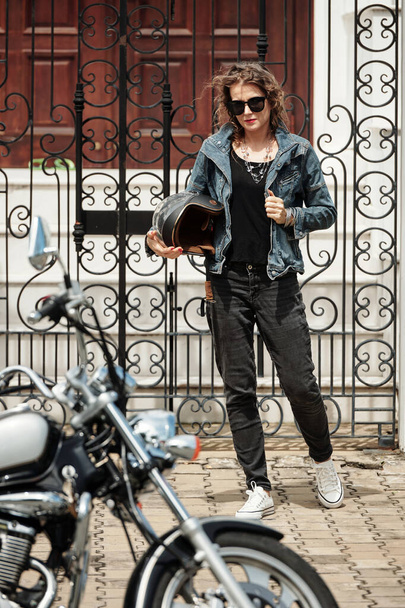彼女のオートバイに歩くヘルメットを持つスタイリッシュな成熟した女性 - 写真・画像