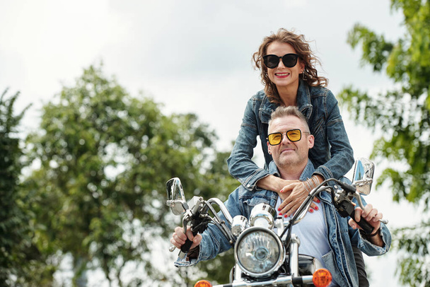 クール幸せな成熟したカップルでデミンジャケットに乗って都市でバイク - 写真・画像