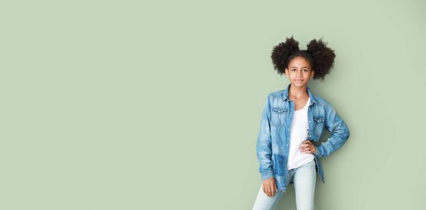 テキストのためのスペースを持つ緑の背景にジーンズのスタイリッシュなアフリカ系アメリカ人の少女 - 写真・画像