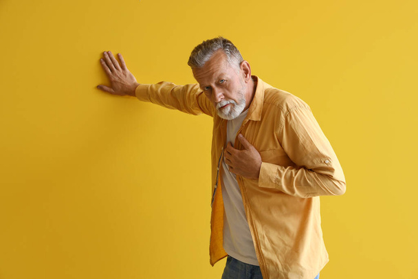 Mature man having heart attack on yellow background - Photo, Image