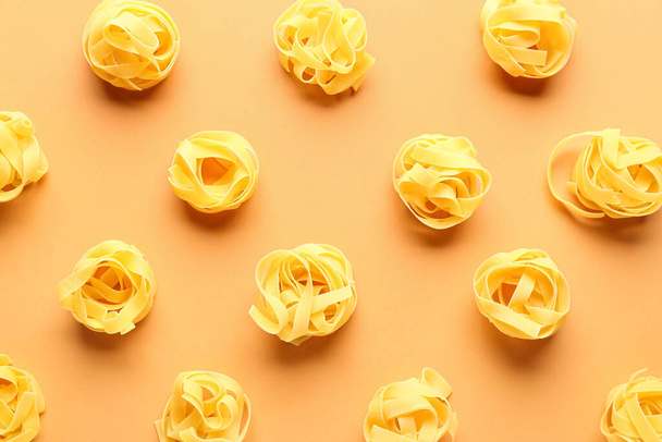 Samenstelling met ongekookte tagliatelle pasta op beige achtergrond - Foto, afbeelding