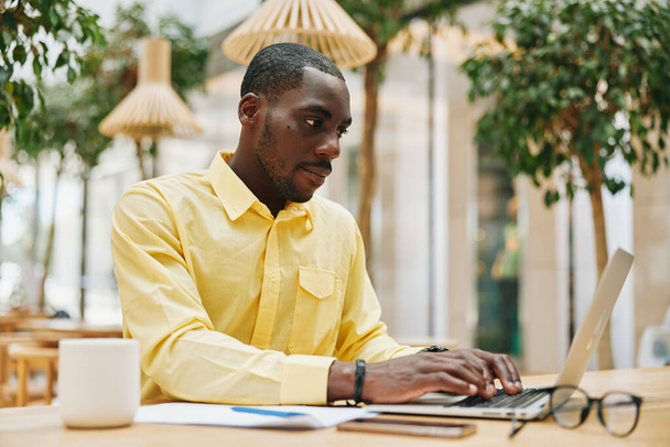 Мужчина черный компьютер работает современные взрослые технологии бизнес молодой бизнесмен образ жизни человека мужской ноутбук, используя сидя африканский профессиональный стол офис - Фото, изображение