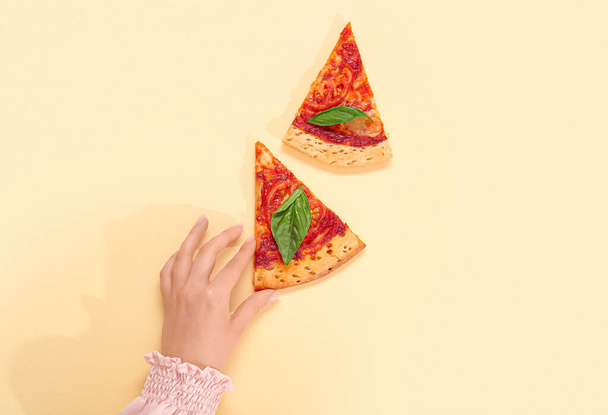 Femme prenant une tranche de pizza savoureuse sur fond jaune - Photo, image