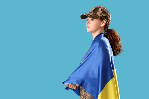 Young female soldier with flag of Ukraine on light blue background - Photo, Image
