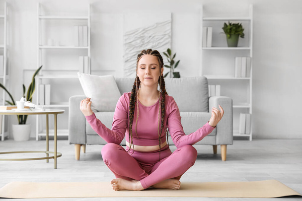 Młoda kobieta z dredami medytująca w domu - Zdjęcie, obraz