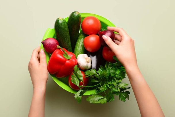 Nő gazdaság színező friss zöldség és zöldség világoszöld háttér - Fotó, kép