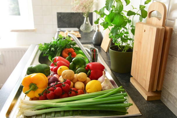 Świeże warzywa i owoce na metalowym zlewie z naczyniami w kuchni - Zdjęcie, obraz