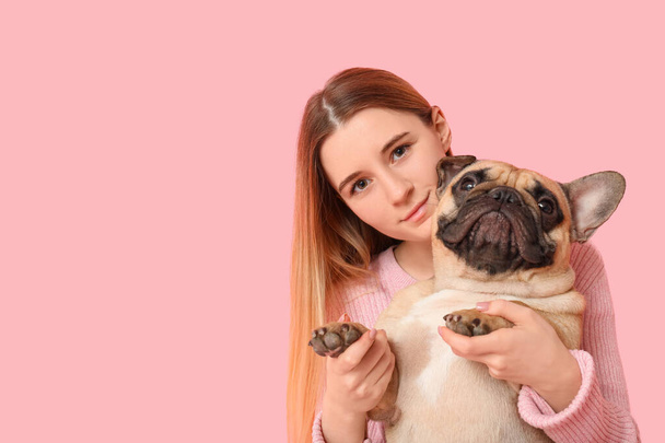 Hermosa mujer joven con lindo perro pug sobre fondo rosa - Foto, imagen