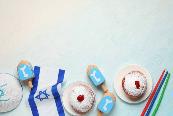 Composizione Hanukkah con ciambelle, dreidel, candele e bandiera israeliana su sfondo azzurro - Foto, immagini